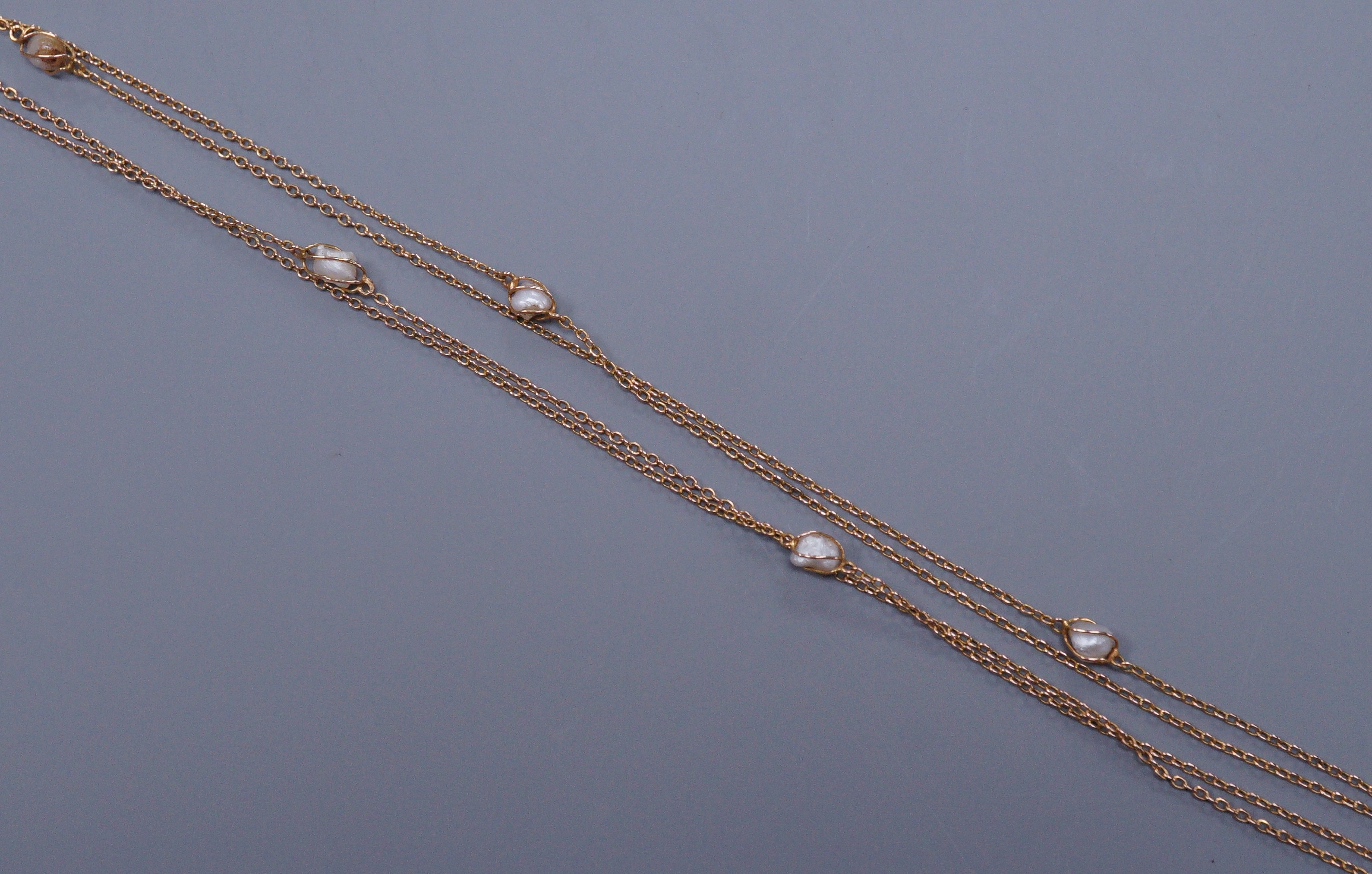 An early 20th century unmarked gold and baroque pearl chain necklace, 137cm